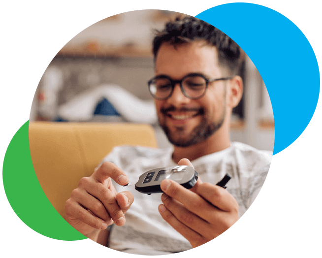 A man sitting down and smiling as he checks his glucose levels. 